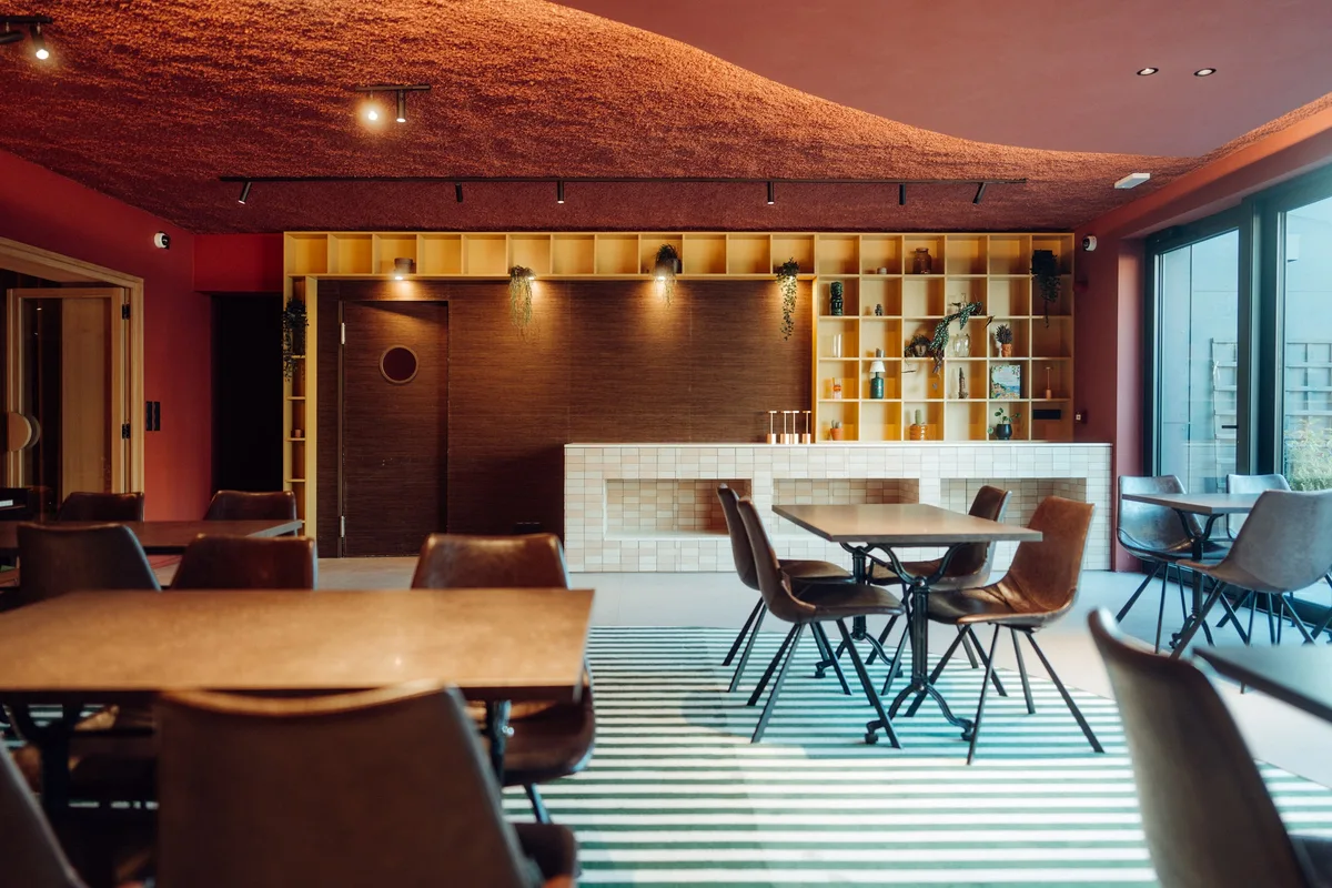 Salle de restaurant et étagères jaunes de la Maison Melba, moquette rayée sur sol en béton ciré