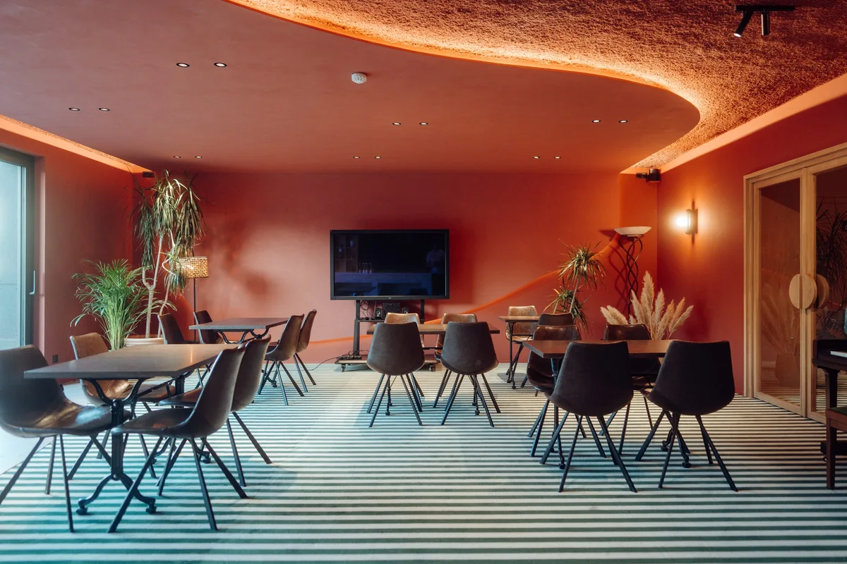 Restaurant de la Maison Melba avec murs rouges et tables, sol en béton ciré et moquette rayée