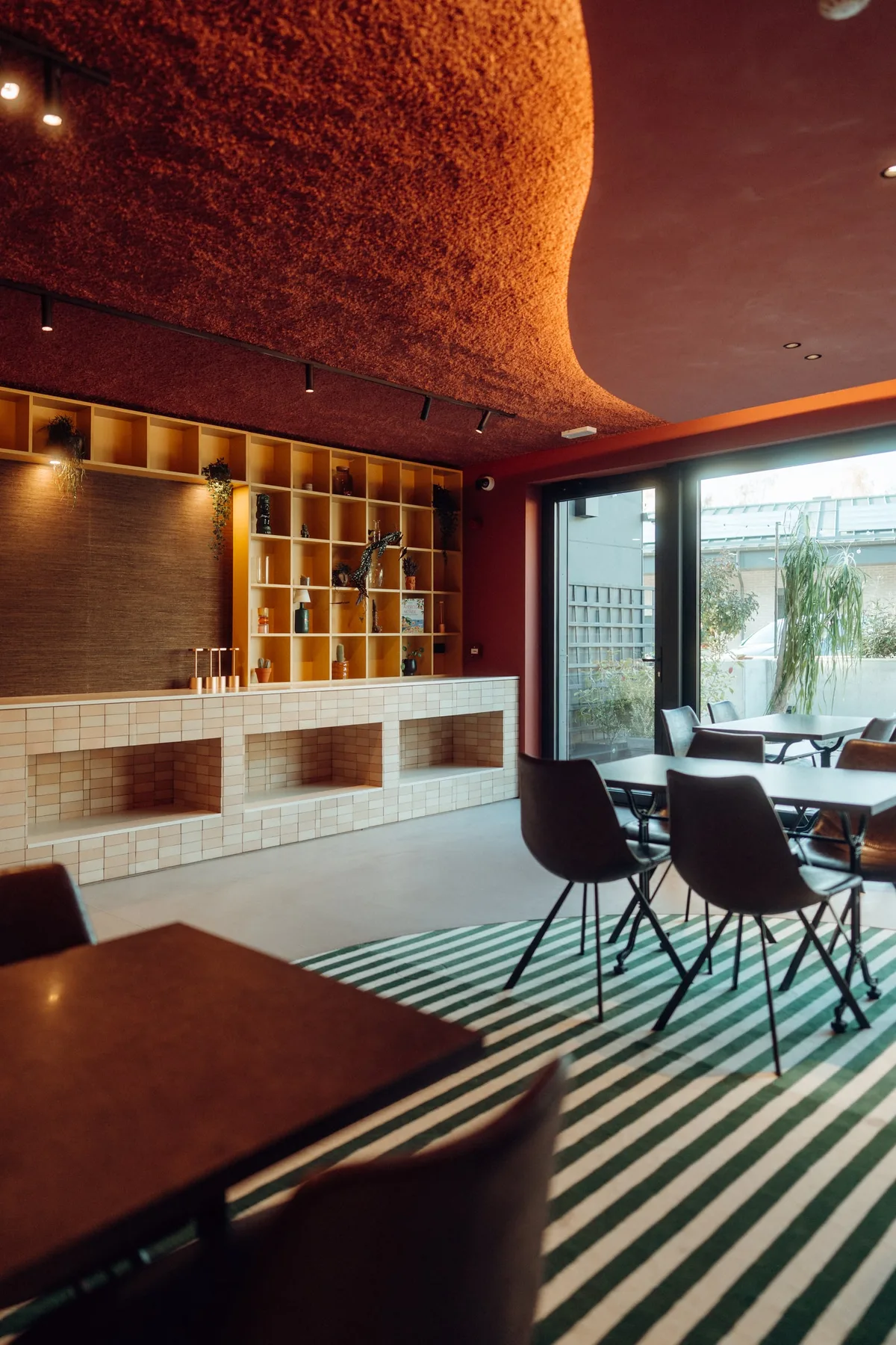 Salle du restaurant de la Maison Melba avec bibliothèque jaune et grande baie vitrée, sur béton ciré