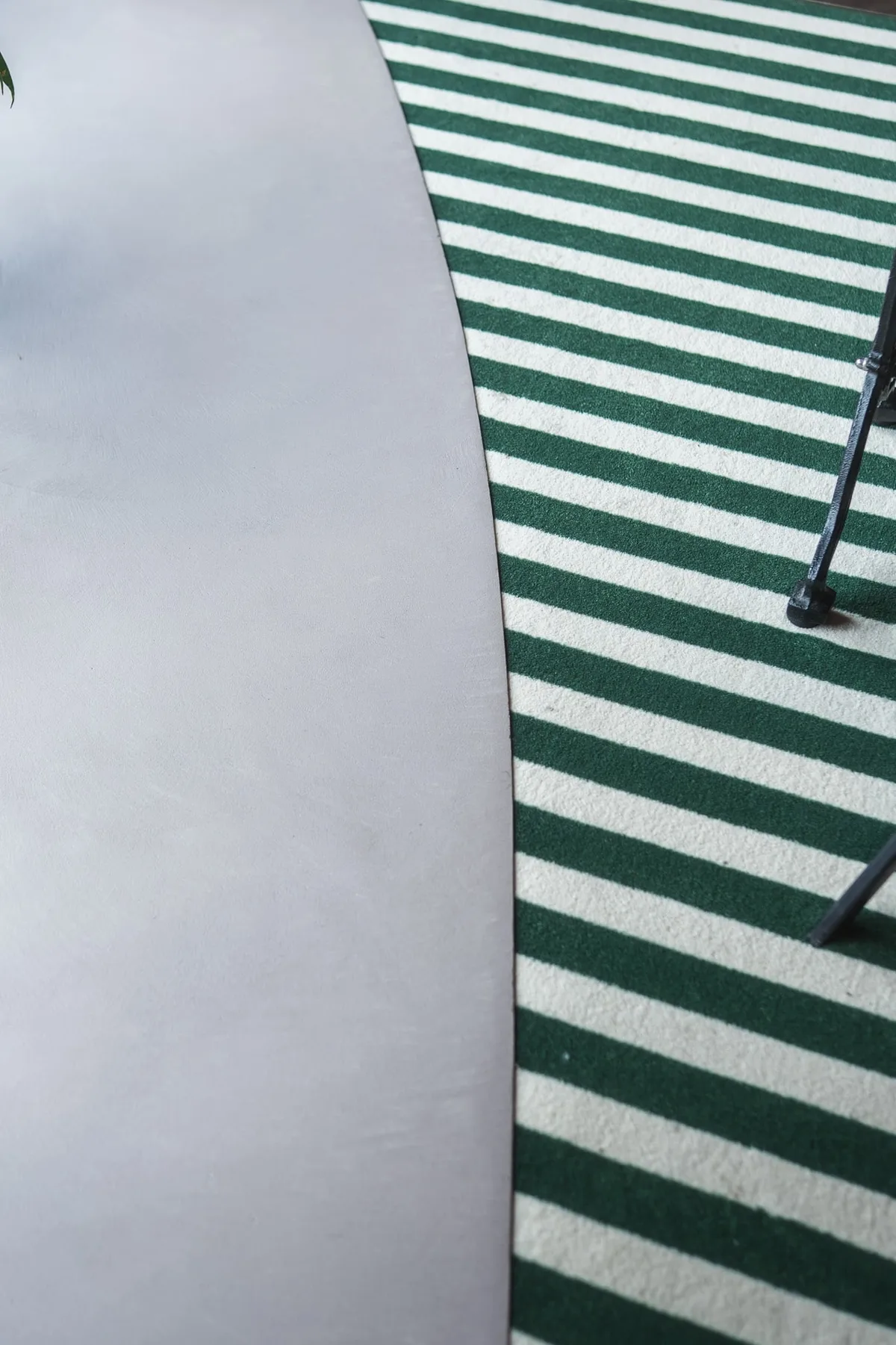 Détail de la jonction entre le béton ciré clair et la moquette rayée vert et blanc