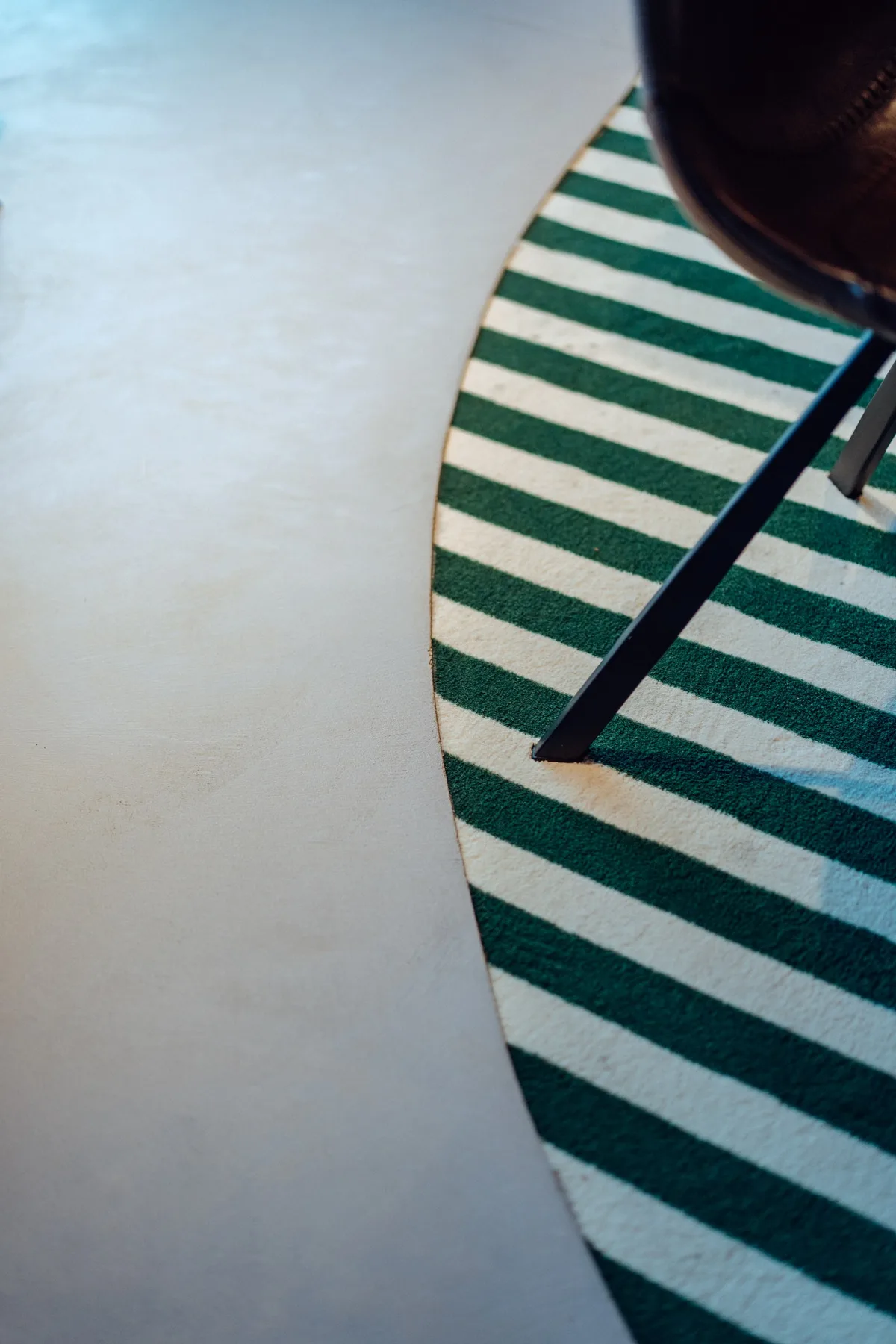 Moquette rayée vert et blanc et rambarde, à la limite d’un sol en béton ciré lisse