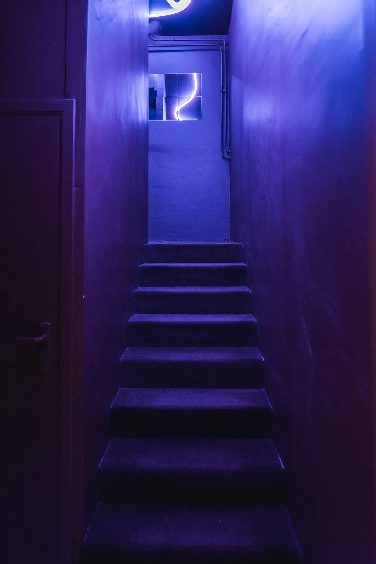 Escalier de la Maison Melba éclairé en violet, marches recouvertes de moquette