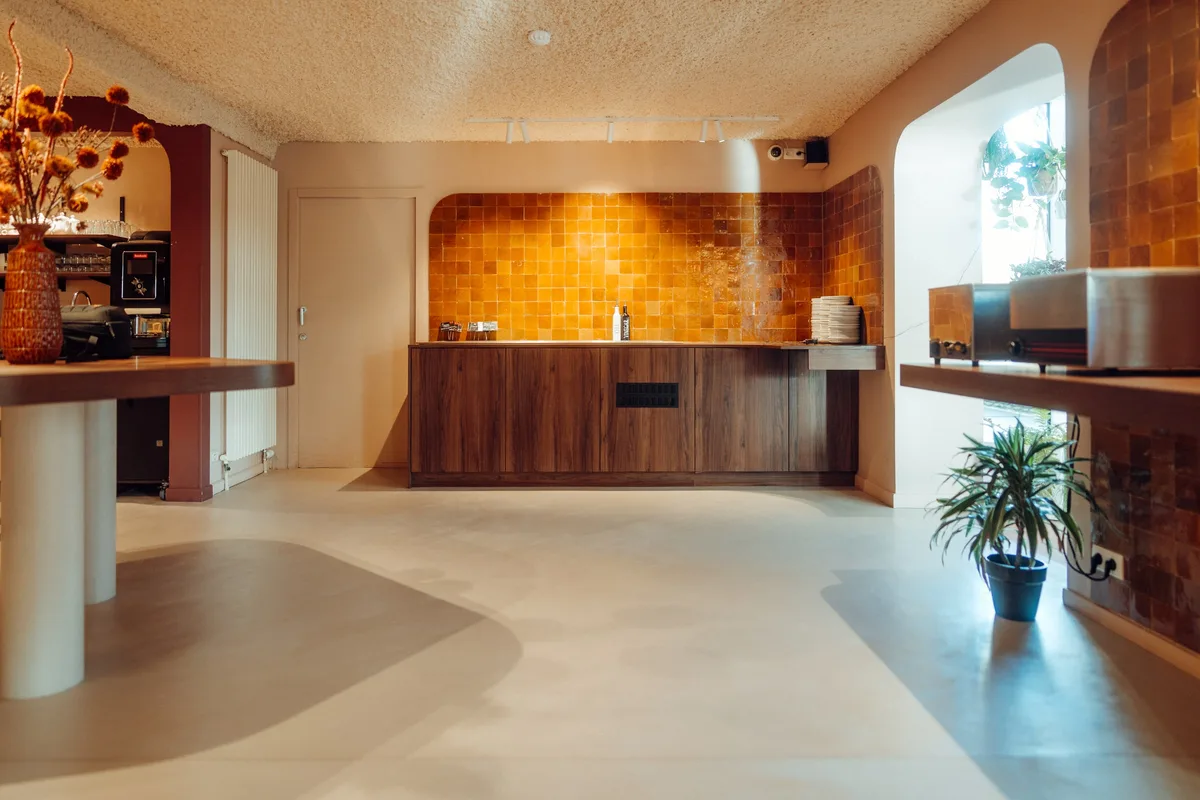 Coin café de la Maison Melba avec meuble en bois et carreaux orange, sol en béton ciré