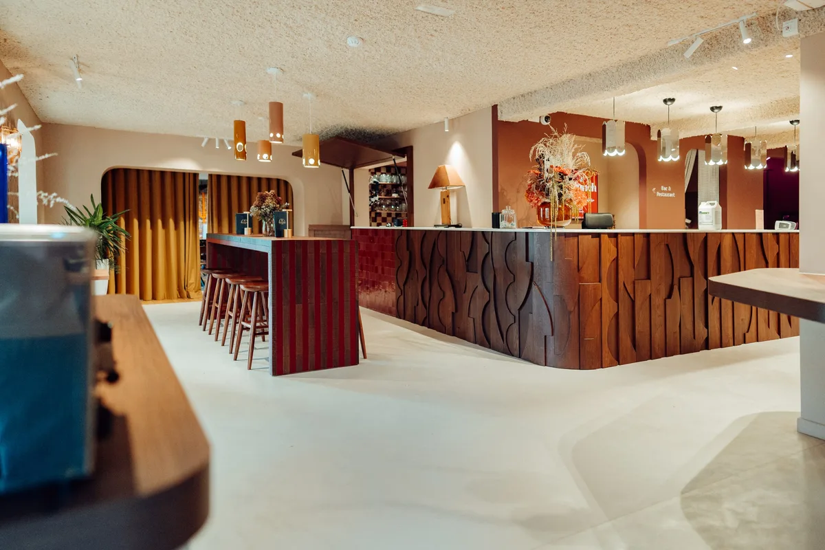 Bar et comptoir de service de la Maison Melba vus depuis la salle, sol en béton ciré clair