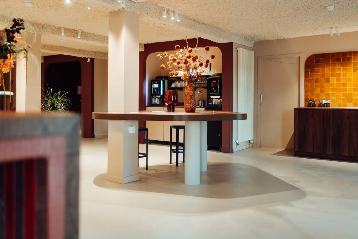 Table haute ronde et espace café de la Maison Melba, sol en béton ciré avec zone courbe plus foncée