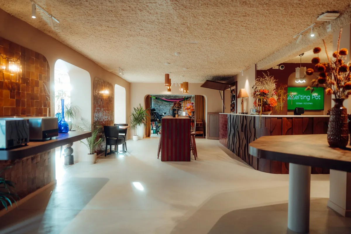Entrée de la Maison Melba à Bastogne, sol en béton ciré clair devant le comptoir en bois sculpté