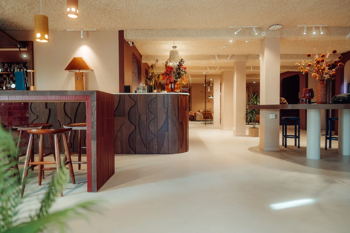Bar et tabourets en bois à la Maison Melba, sur un sol en béton ciré clair