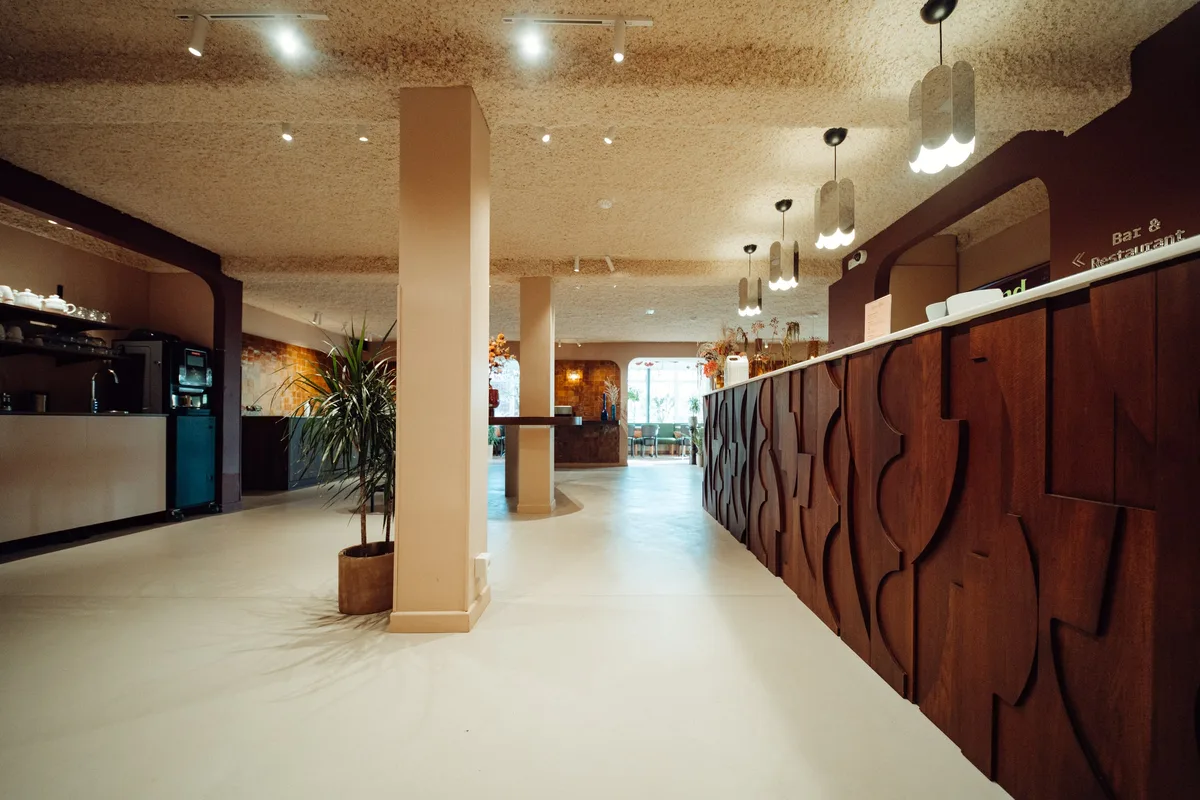 Long comptoir en bois sculpté et sol en béton ciré dans le hall de la Maison Melba
