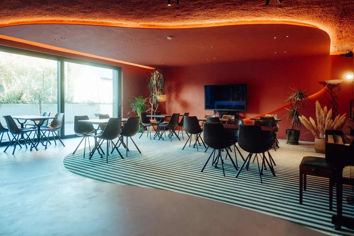 Restaurant de la Maison Melba à Bastogne : moquette rayée dans un tracé courbe, bordée par le béton ciré