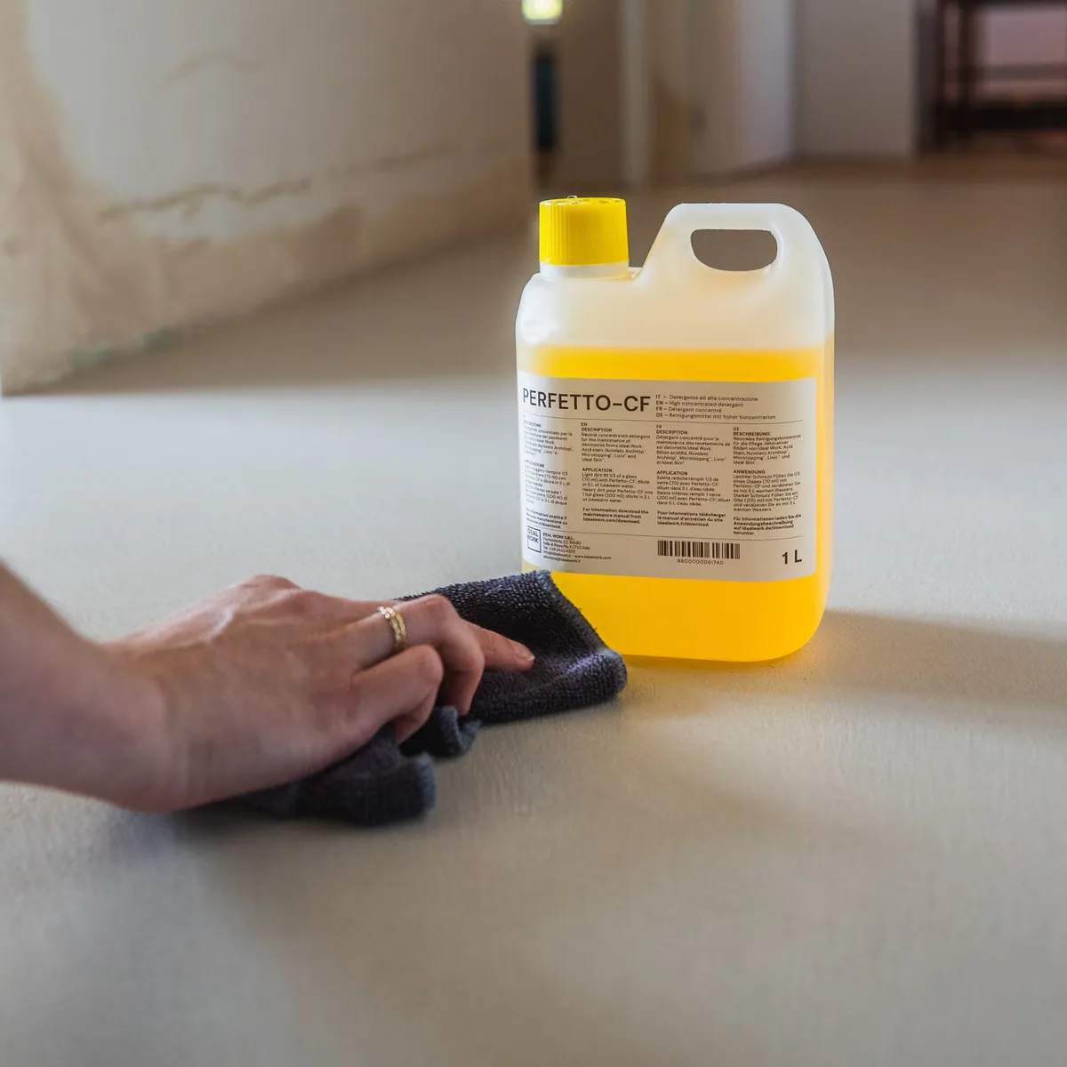 Une main essuie un béton ciré avec le nettoyant Perfetto CF