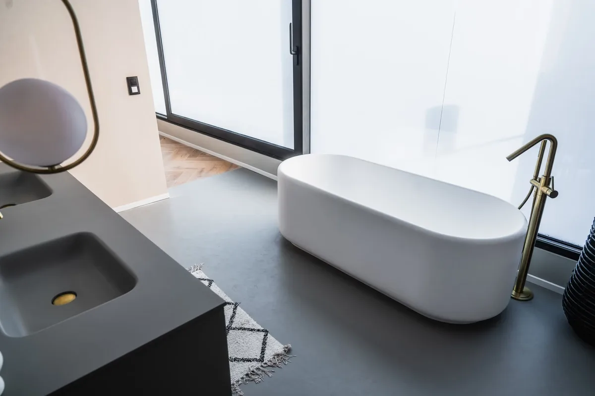Salle de bain avec baignoire îlot et sol gris continu en résine époxy à Walhain