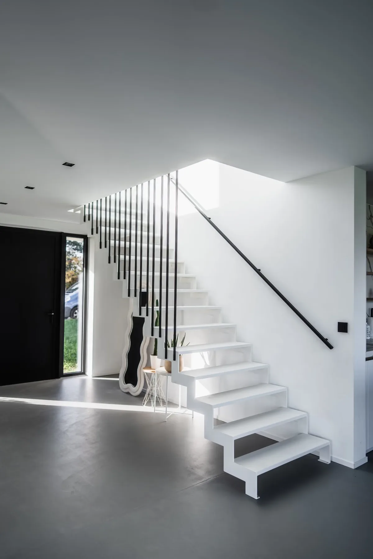 Escalier blanc et sol gris continu en résine époxy dans une maison neuve à Walhain