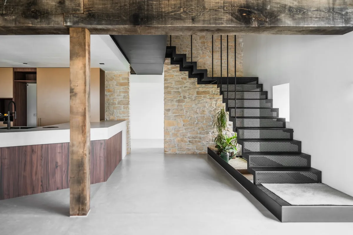 Sol en béton ciré gris clair, escalier métallique et cuisine dans une maison contemporaine